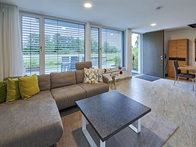 Wohnbereich mit Sofa, Essplatz und bodentiefen Fenstern