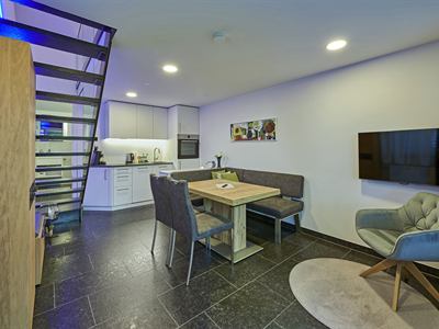 Wohnbereich mit offener Küche, Ecksitzbank und Treppe ins Obergeschoss