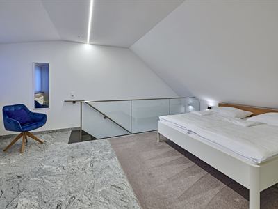 Schlafbereich im Obergeschoss mit Doppelbett und Sessel